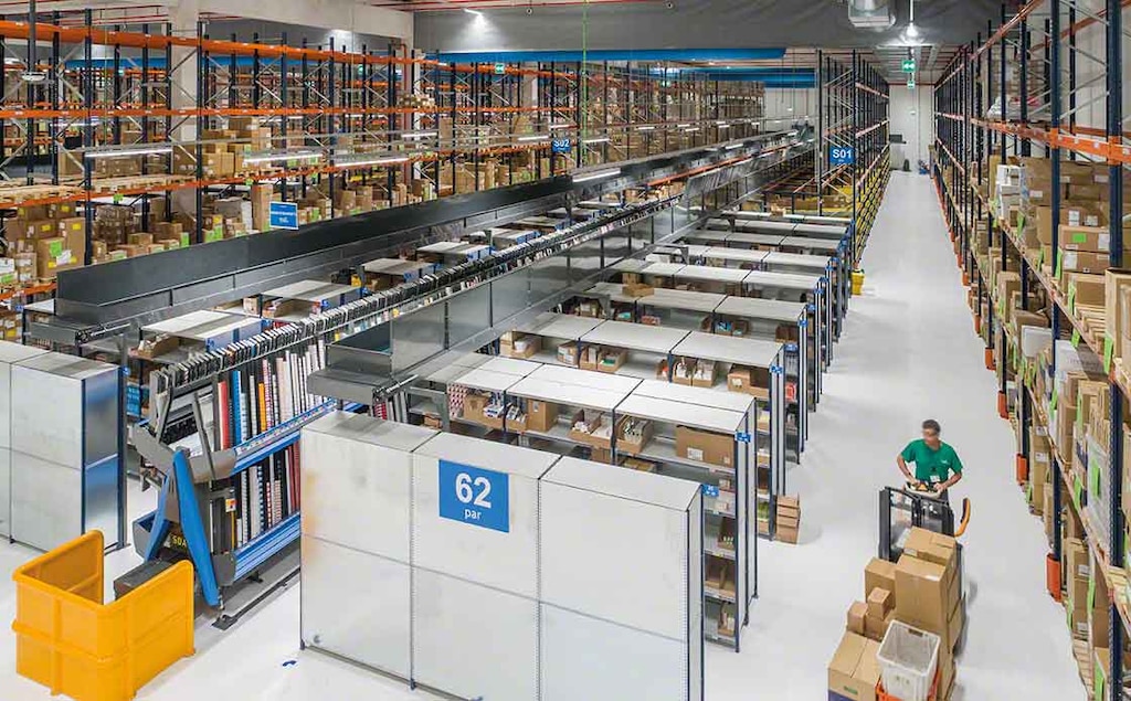 An operator performs warehouse picking tasks, aided by a pallet lorry